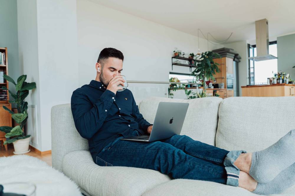 Mann auf Sofa mit MacBook auf dem Schoß verkauft sein Auto schnell an autolos.de