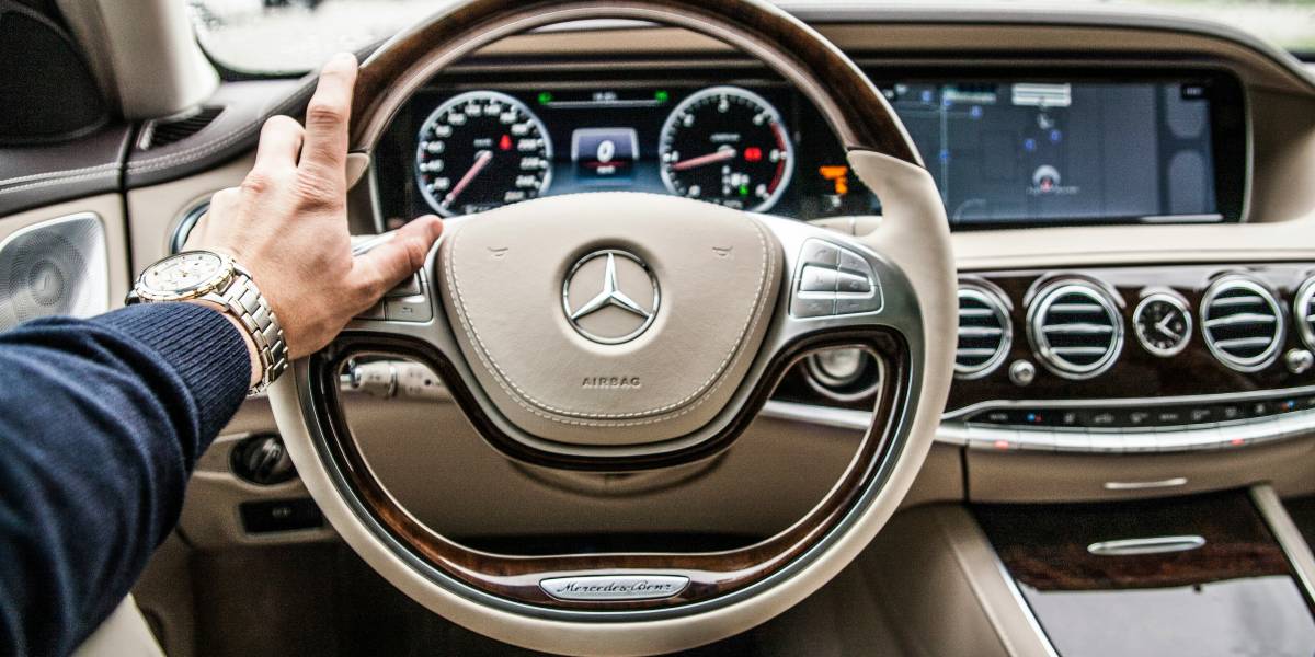 Autofahren im Alter: Linke Hand eines älteren Herren am Lenkrad eines Mercedes.
