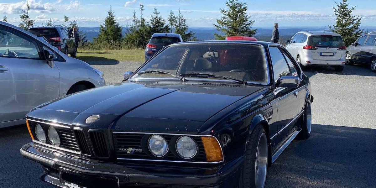 Youngtimer verkaufen: Dunkelblauer älterer BMW auf Aussichtsparkplatz. Im Hintergrund weitere Autos